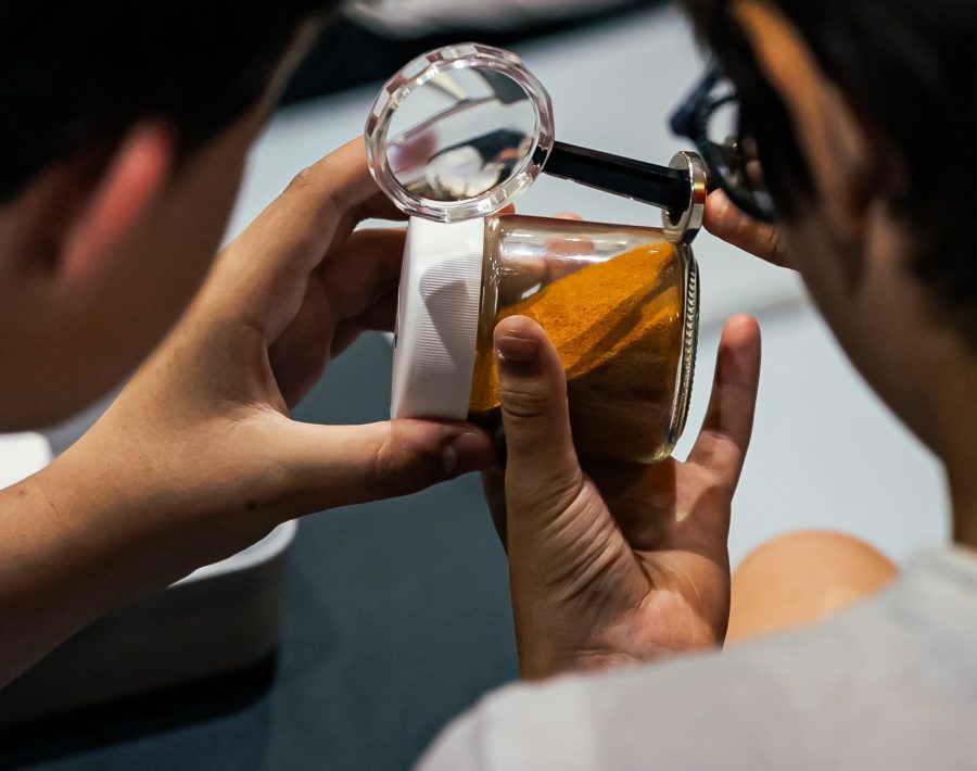 Des enfants observent une poudre avec une loupe dans le cadre de l'atelier Mars Challenge